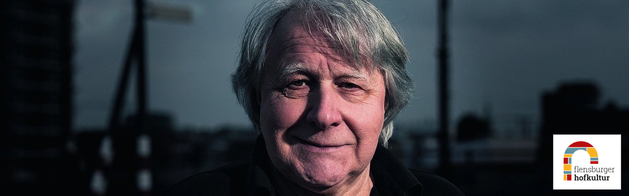Porträt des Musikjournalisten Peter Urban vor städtischer Kulisse